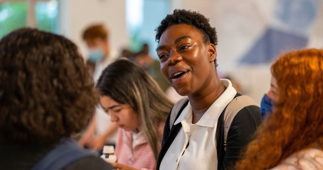 A group of students chatting together in a lively classroom environment.